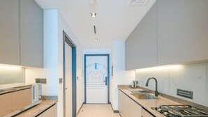 A modern kitchen with a gas stove, sink, and a sign indicating no electrical cooker allowed.