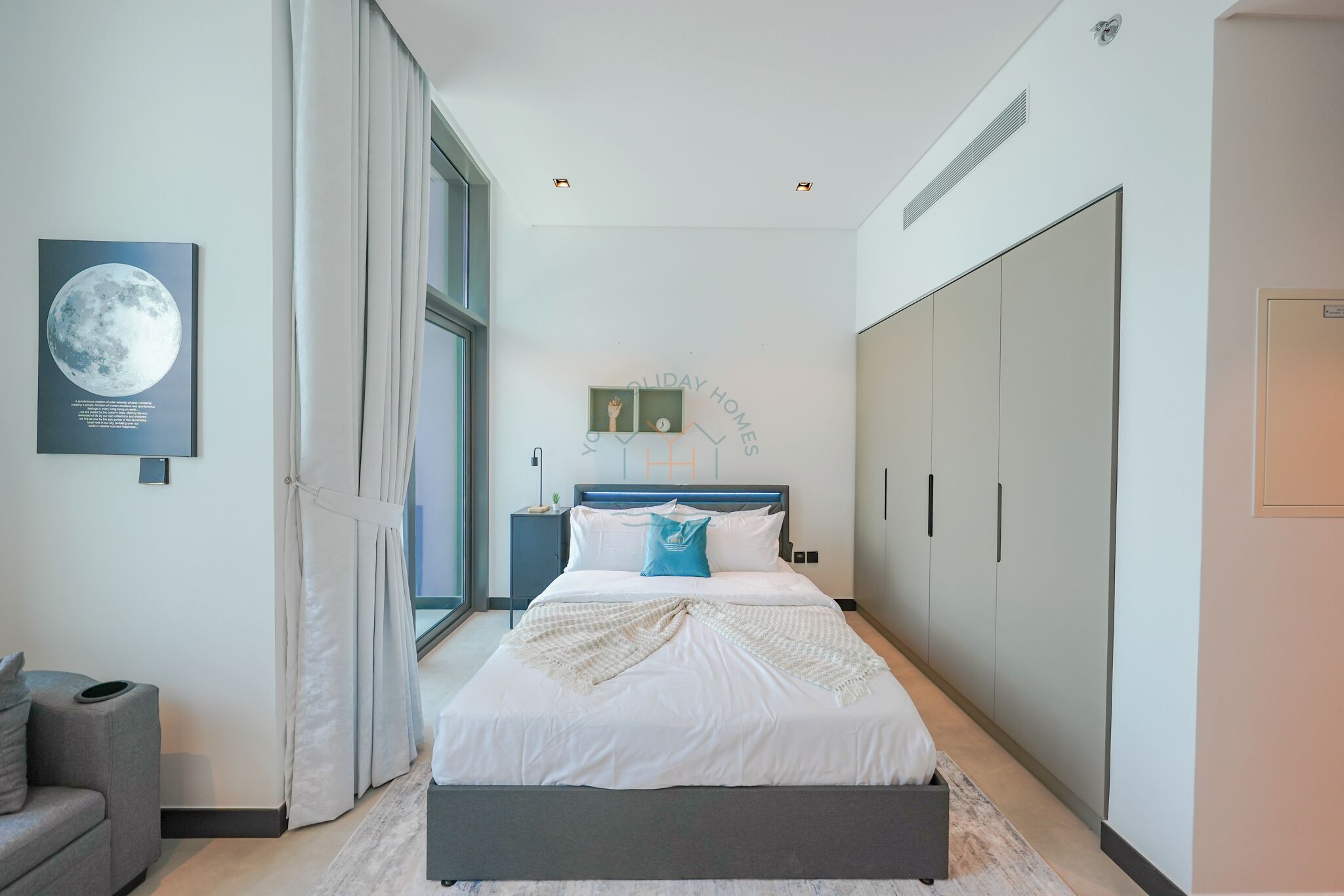 Une chambre moderne avec un grand lit, une table de chevet, une armoire et une fenêtre avec des rideaux.