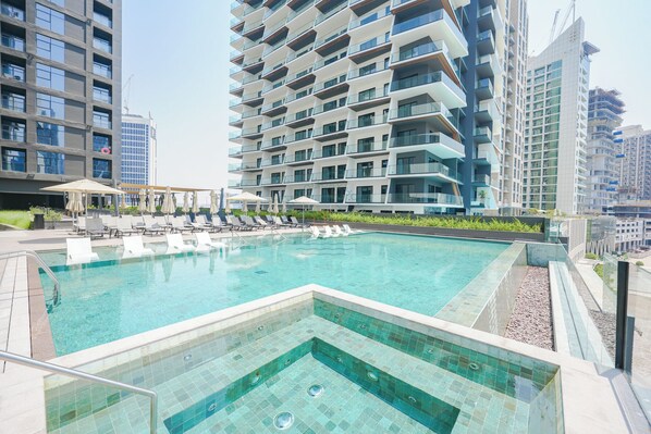 Um hotel moderno com piscina infinita no terraço, várias varandas e vista para edifícios altos ao redor.