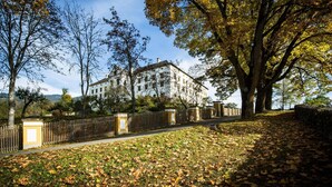 A large, historic building with a symmetrical facade, surrounded by trees and a wooden fence. - Apartment in Kreischberg Near Ski Resort (Sankt Georgen am Kreischberg)