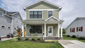 A two-story residential building with a front porch, a small garden, and a mailbox.