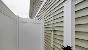 A white exterior wall with a metal bracket and a vertical pipe.