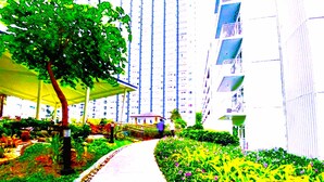 Un sendero bordeado por vegetación y un edificio con balcones.