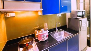 Una cocina compacta con un lavamanos, un microondas y una estufa.