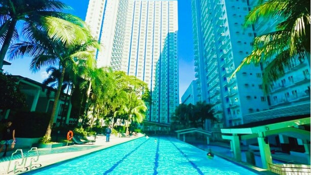 Una piscina con agua azul cristalina, rodeada de edificios altos y palmeras.