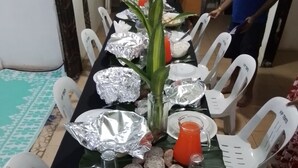 A dining table set with plates, foil-wrapped food, a vase with flowers, and a glass of juice. - Room-outback Retreathotel, Ba Fiji (Ba)