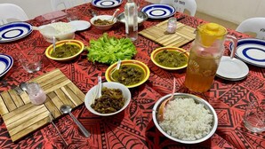 A dining table set with various dishes, including rice, salads, and meat dishes, with a patterned tablecloth and a bottle of water. - Room-outback Retreat Hotel, Ba Fiji (Ba)