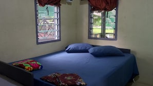 A single bed with a blue mattress and pillows, a colorful blanket, and a window with a curtain. - Room-outback Retreat Hotel, Ba Fiji (Ba)