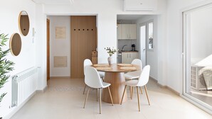 A modern dining area with a round wooden table, white chairs, and a vase with flowers. - Stunning 2-baths apartment with golf and lake view (Sucina)