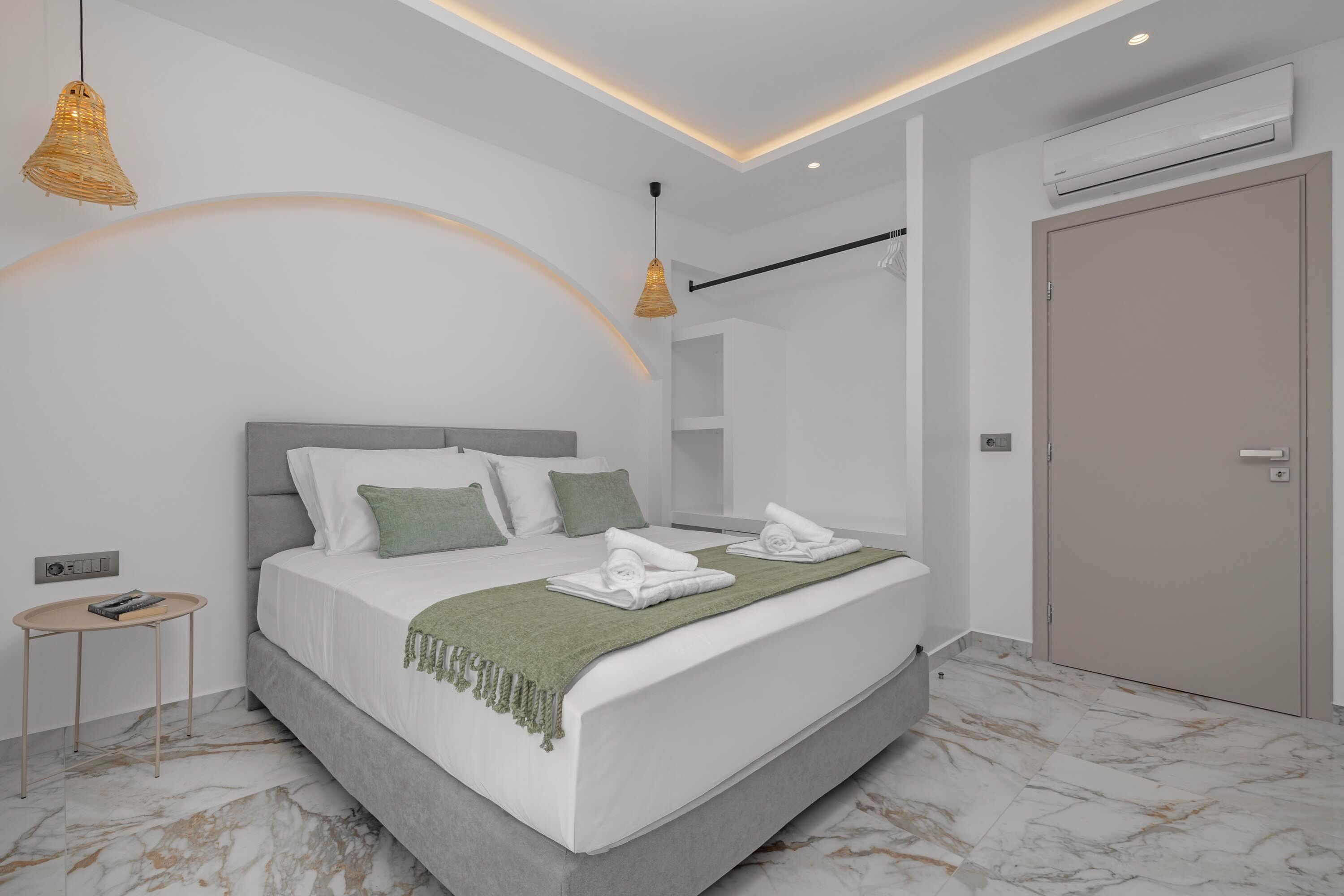 A modern bedroom with a bed, bedside table, and a wardrobe.
