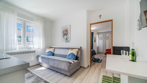A modern living room with a sofa, a dining table, and a kitchen area. - Rooftop Terrace Apartment in Zagreb Lower Town (Zagreb)