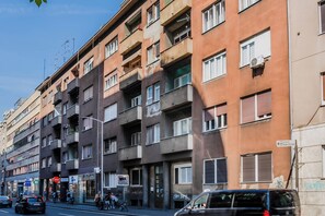 A multi-story building with balconies, a street in front, and a sign indicating a direction. - Rooftop Terrace Apartment (Zagreb)