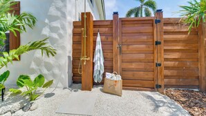 A wooden gate, a towel, and a bag near a white wall with a window. - Walk to Gulf: Luxe Luau-themed Gem in Holmes Beach (Holmes Beach)