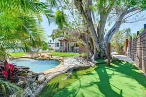 Ein Garten mit Schwimmbad, Baum und Haus.