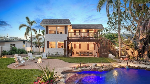 A two-story house with a backyard featuring a swimming pool, outdoor seating, and a fire pit. - Walk to Gulf: Luxe Luau-themed Gem in Holmes Beach (Holmes Beach)