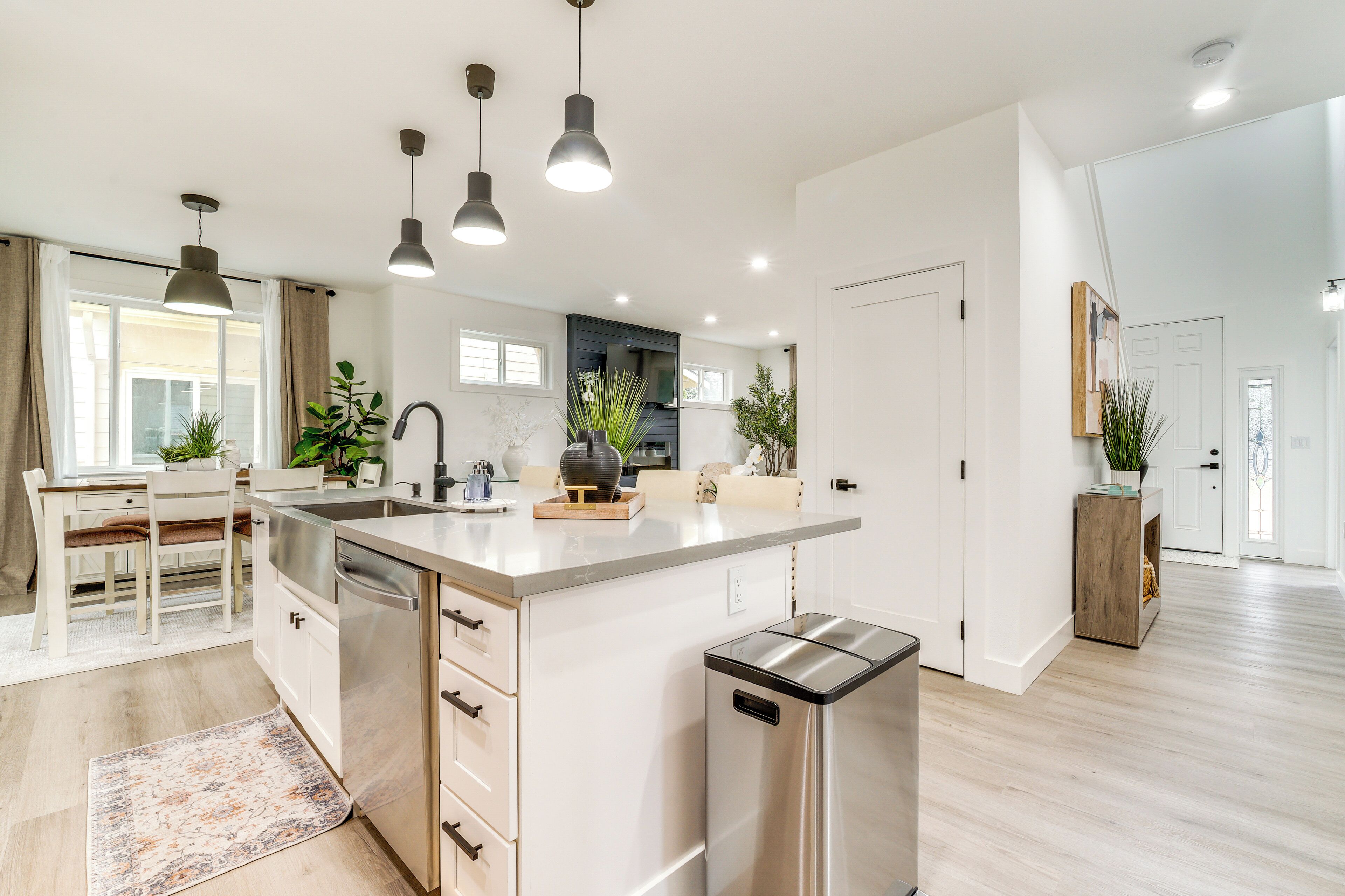 Una cocina moderna con una isla central, electrodomésticos de acero inoxidable, iluminación colgante y vistas al área de estar contigua.