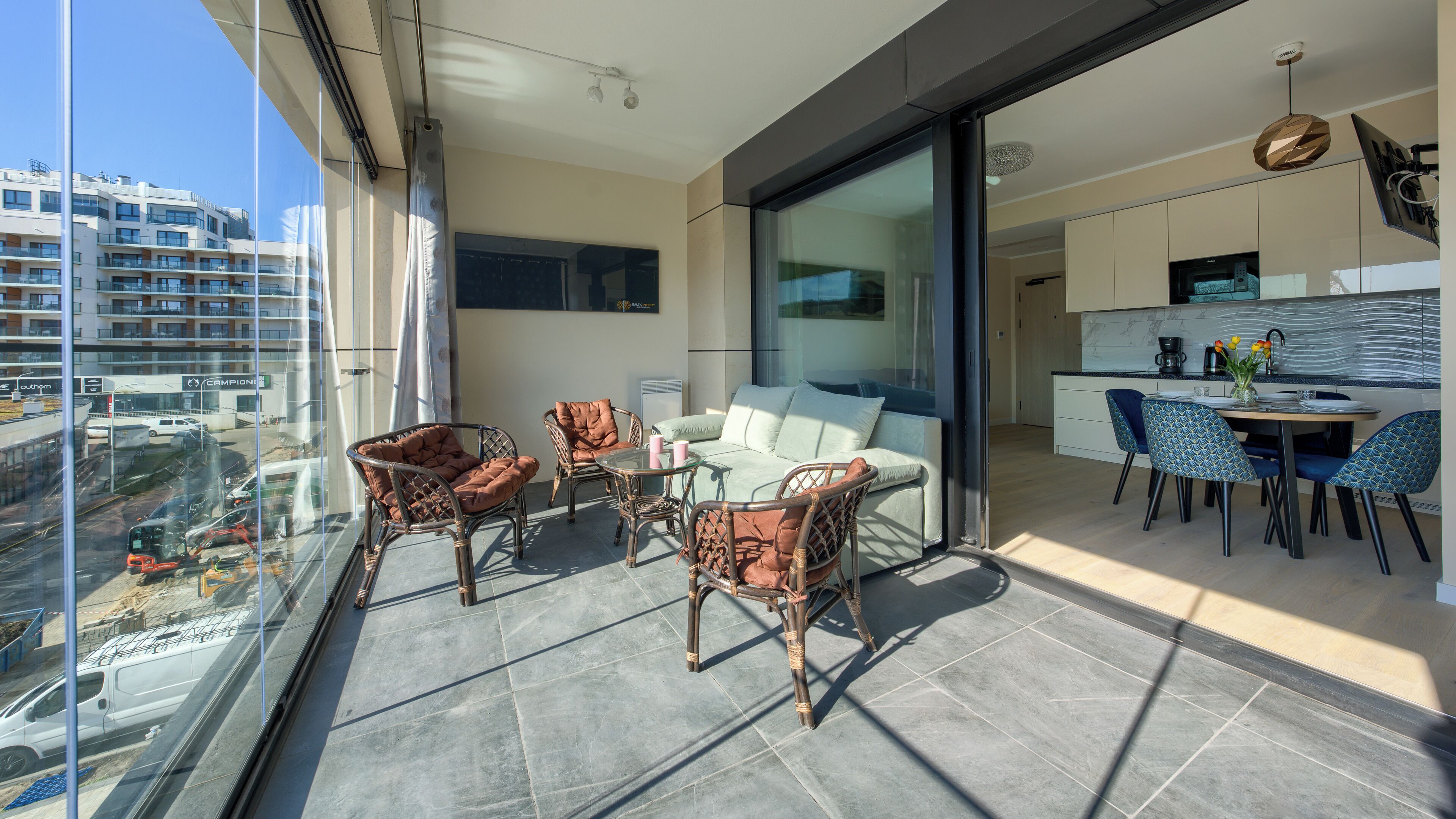 A balcony with wicker furniture, a sofa, and a dining table with chairs.