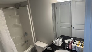 Ein Badezimmer mit Dusche, Toilette, Waschbecken und Spiegel.