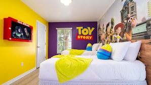 Une chambre à coucher avec un lit, une télévision et une fresque murale représentant des personnages de Toy Story.