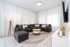A modern living room with a sectional sofa, a round coffee table, and a floor lamp. - Gorgeous 4Bd w Pool at Encantada Resort 8523 (Kissimmee)
