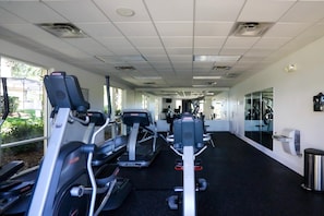 A gym with treadmills, exercise bikes, and mirrors on the walls.