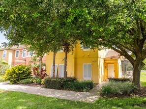 A yellow building with the number 8523, surrounded by greenery and a sidewalk. - Gorgeous 4Bd w Pool at Encantada Resort 8523 (Kissimmee)
