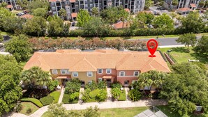 A multi-story residential building with a red-tiled roof, surrounded by lush greenery and a parking area. - Gorgeous 4Bd w Pool at Encantada Resort 8523 (Kissimmee)