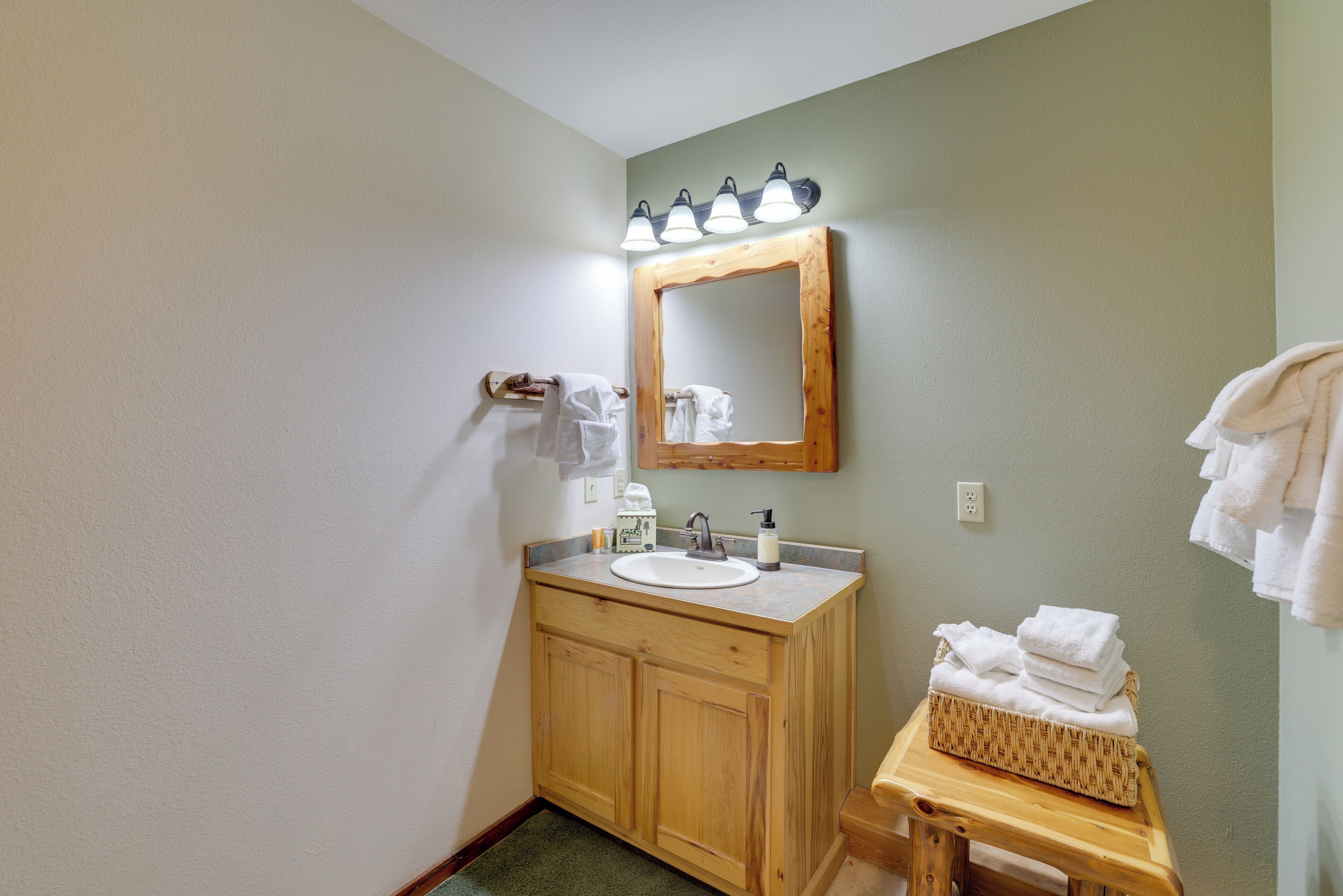 A bathroom with a wooden vanity, a sink, a mirror, and a towel rack.