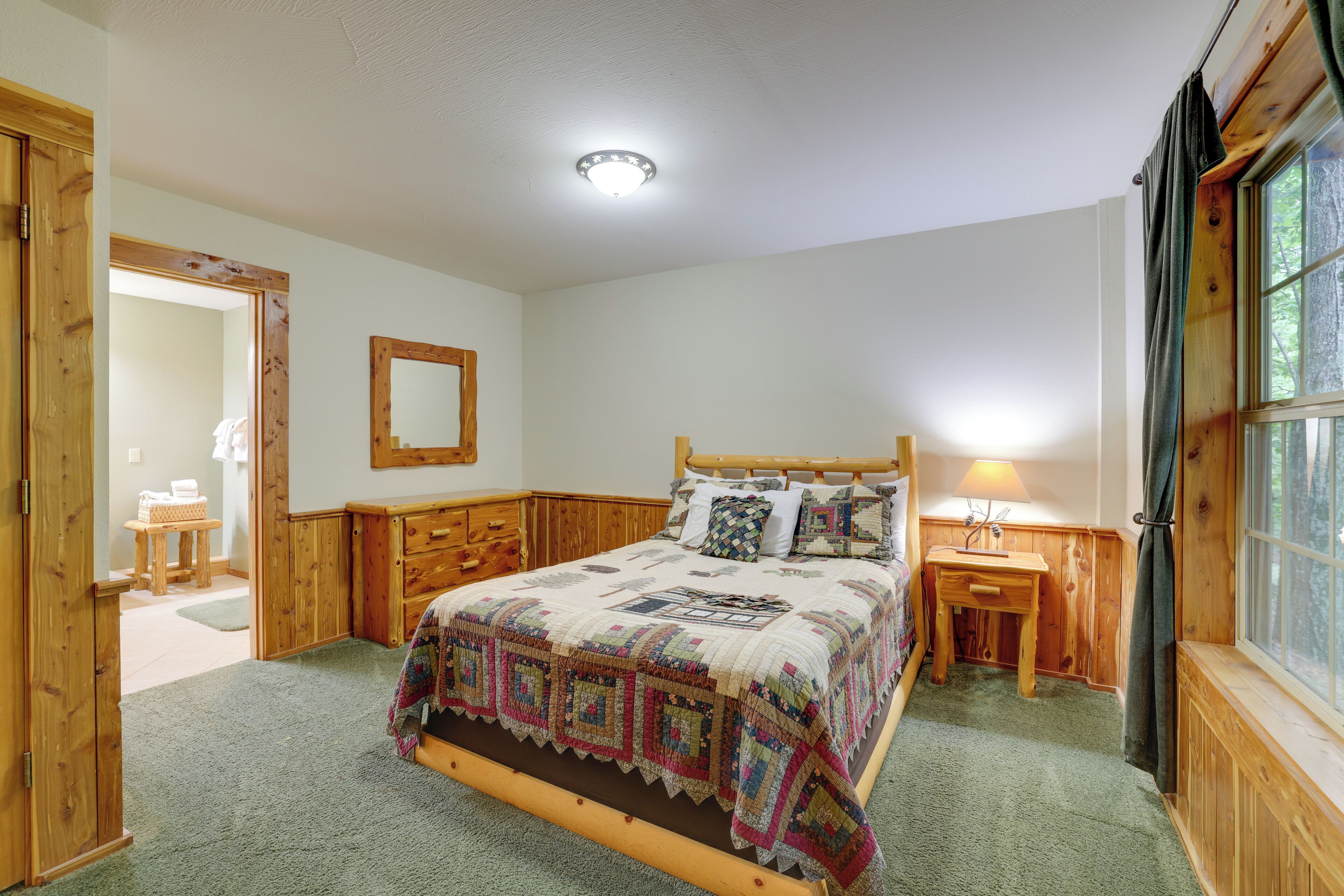 A bedroom with a wooden bed, a nightstand, a mirror, and a window with curtains.