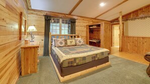 A wooden cabin bedroom with a bed, a nightstand, a lamp, and a closet.