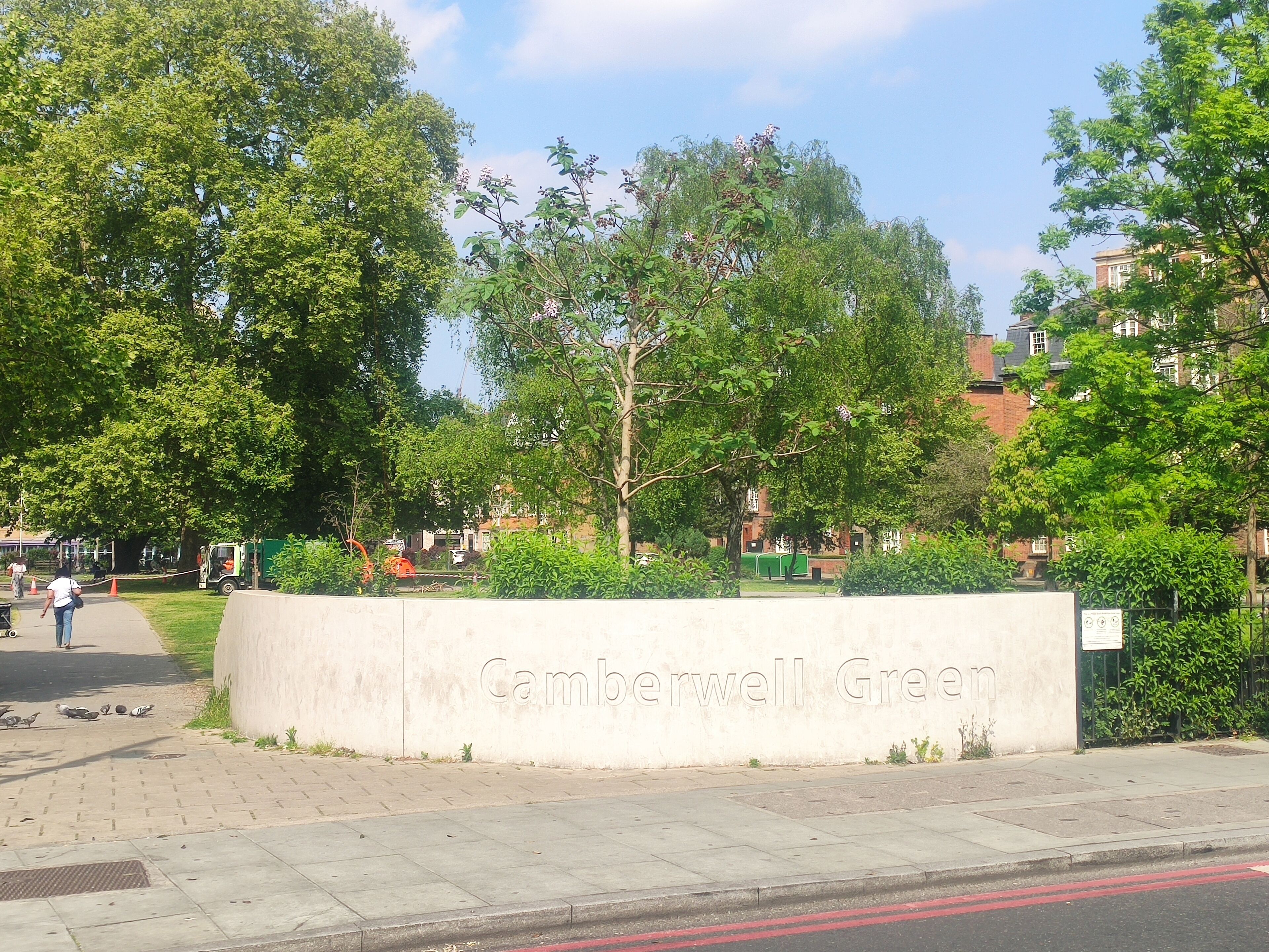 A sign reading "Camberwell Green" with a paved walkway and trees in the background.
