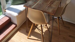 A cozy seating area with a wooden table, two chairs, a green cushion, and a framed picture of London. - Stylish Stay in Camberwell (London)