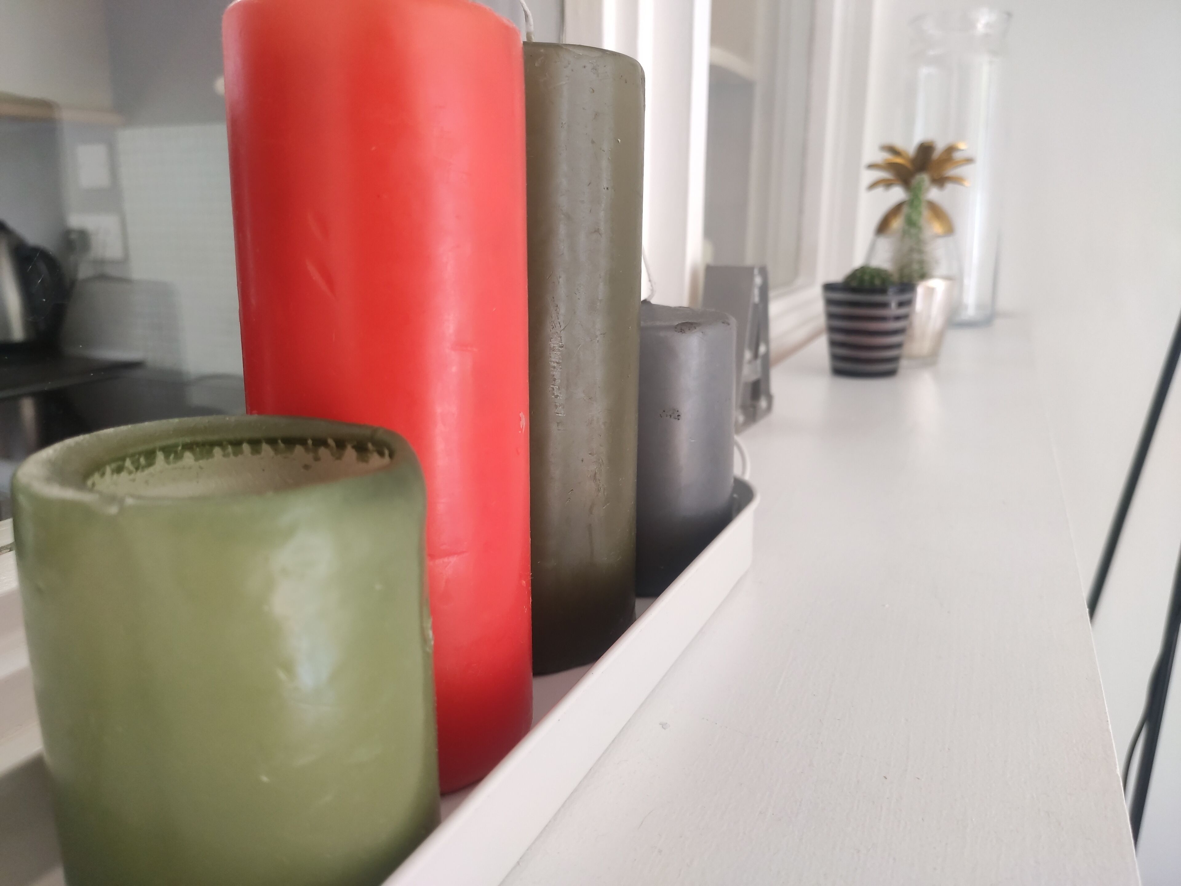A shelf with various cylindrical objects, including a red, a black, and a green container.