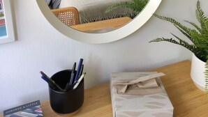 A bedroom with a bed, a bedside table with a lamp, a mirror, and a potted plant. - Stylish Stay in Camberwell (London)