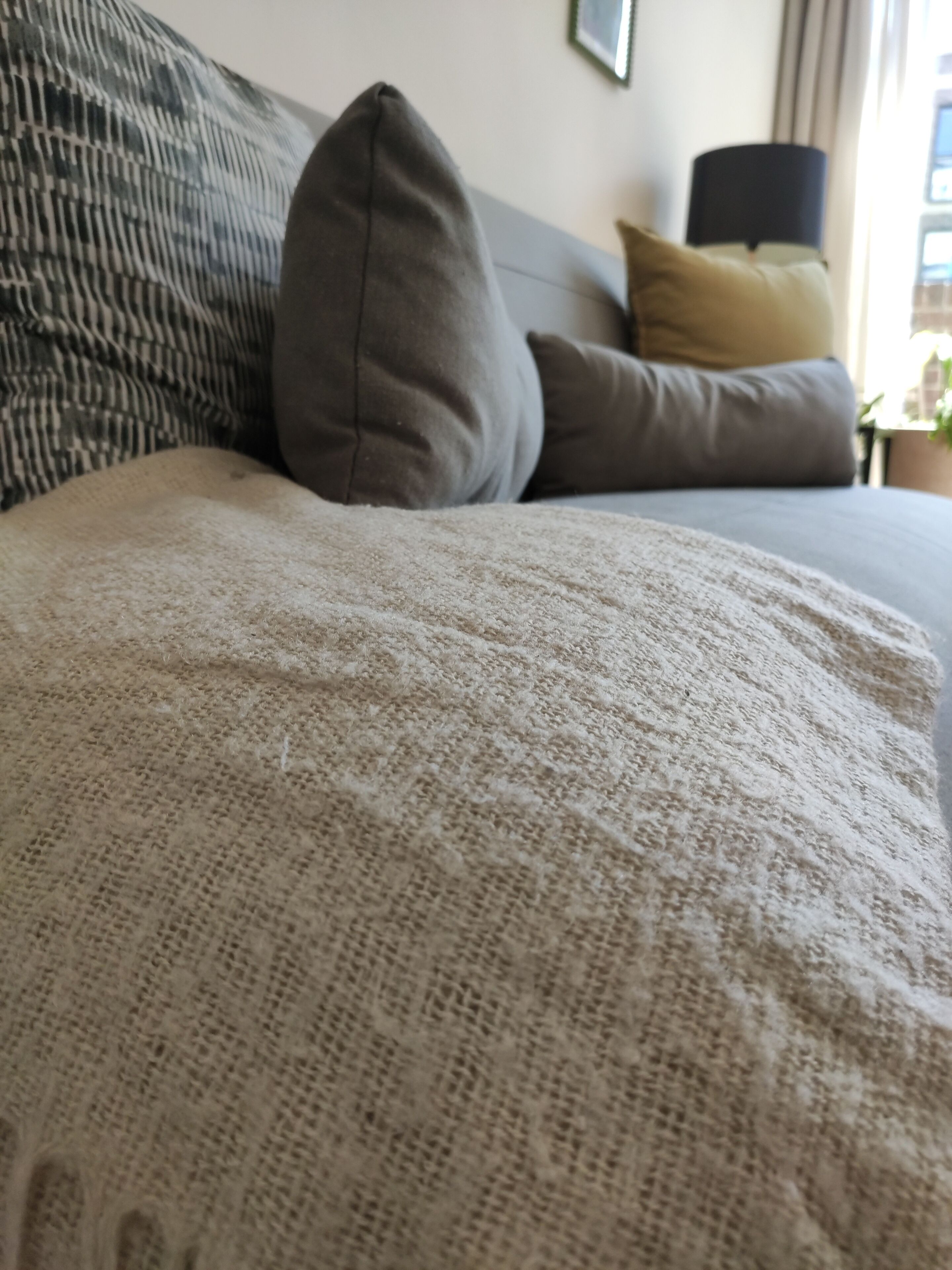 Un lit avec une couverture à motifs, un oreiller gris et un autre oreiller à motifs.