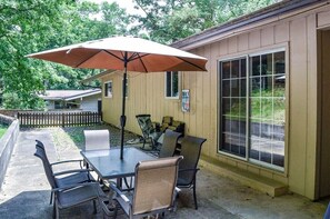 An outdoor patio with a table and chairs, a large umbrella, and a building with large windows. - 05234 - 34 South Pego Way (Hot Springs)