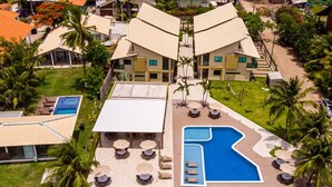 A resort with a large pool area, multiple lounge chairs, and a well-maintained lawn. - Casa BeiraMar 4QTS Piscina-SH031 (Ipojuca)