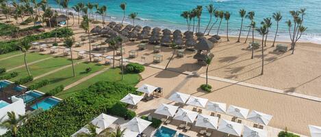 An aerial view of a resort with a pool, beach, and ocean.
