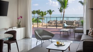 A modern living room with a large window overlooking a beach. - The Excellence Club at Finest Punta Cana Adults Only - All Inclusive (Punta Cana)