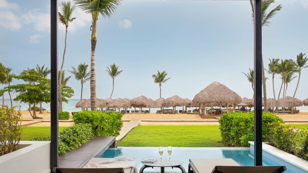 A poolside area with a view of the beach, palm trees, and thatched umbrellas. - The Excellence Club at Finest Punta Cana Adults Only - All Inclusive (Punta Cana)