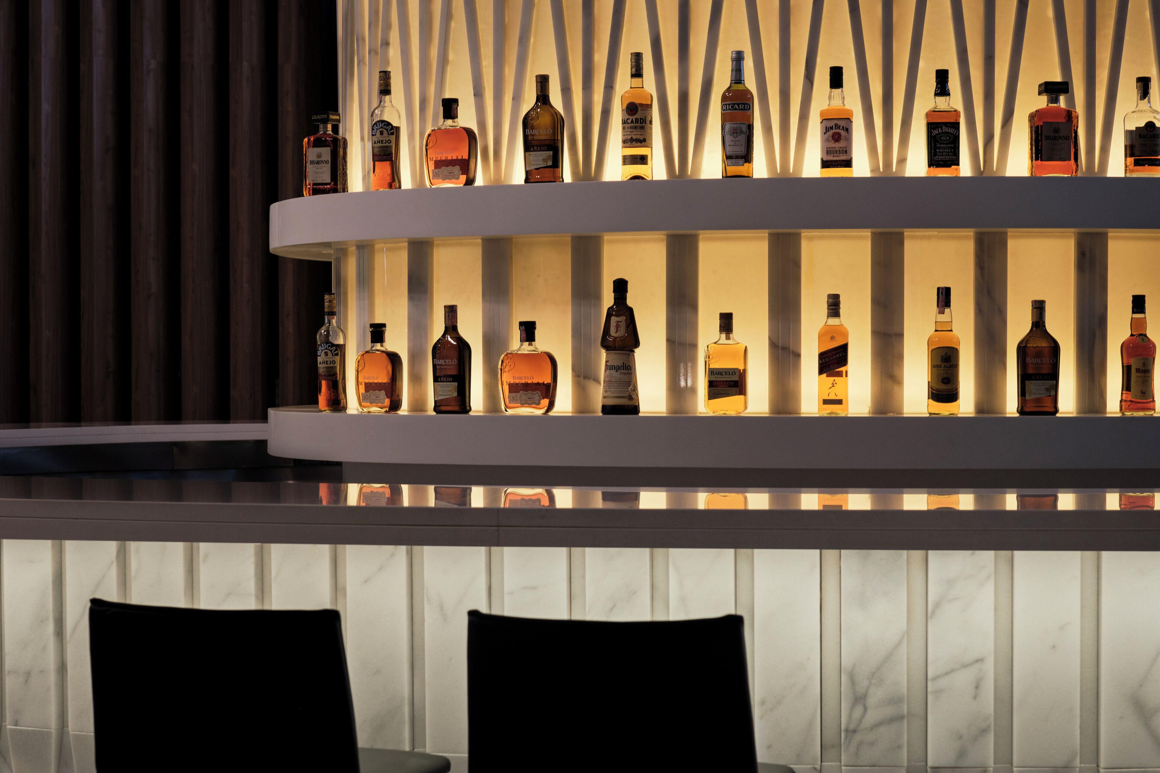 Un bar avec de nombreuses étagères remplies de bouteilles d’alcool.