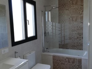 Uma casa de banho com chuveiro, sanita e banheira.