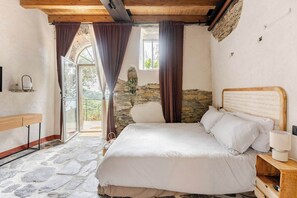Un dormitorio con pared de piedra, estructura de cama de madera y vistas al exterior.