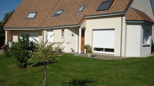 A two-story house with a sloped roof, a garage, and a small garden with a tree. - Room for rent for all events on the circuit de la sarthe (Changé)
