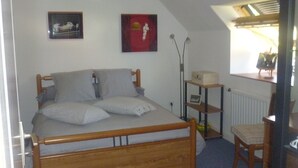 A bedroom with a wooden bed, a chair, a desk, and two wall-mounted pictures. - Room for rent for all events on the circuit de la sarthe (Changé)
