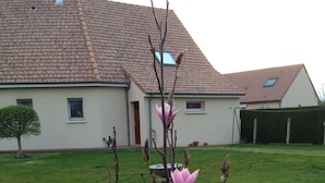 A residential building with a tiled roof, a visible chimney, and a well-maintained lawn. - Room for rent for all events on the circuit de la sarthe (Changé)