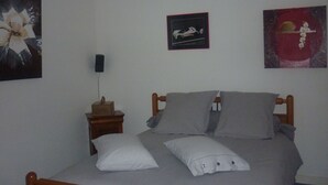 A bedroom with a bed, pillows, a nightstand, and wall art. - Room for rent for all events on the circuit de la sarthe (Changé)