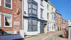A row of terraced houses with distinct architectural styles, including a bay window and a white facade with a blue trim. - Host & Stay | Admiral's View (Whitby)