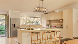 Una cocina moderna con una isla central, taburetes de bar y un ventanal grande.