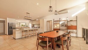 Una cocina moderna con una isla central, taburetes de bar y una mesa de comedor con sillas.